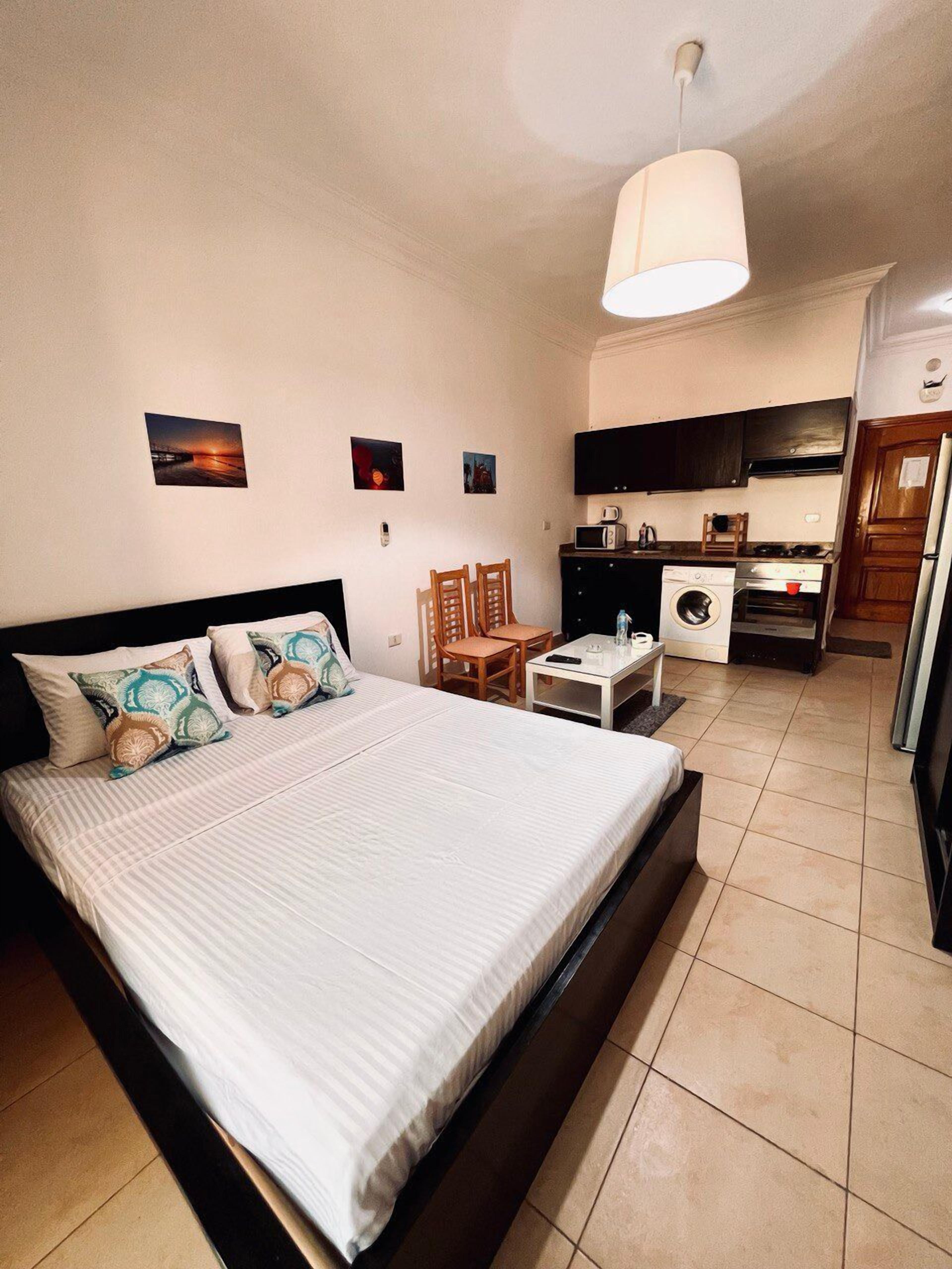 A hotel room with a bed, a desk, a washing machine, and a kitchenette.