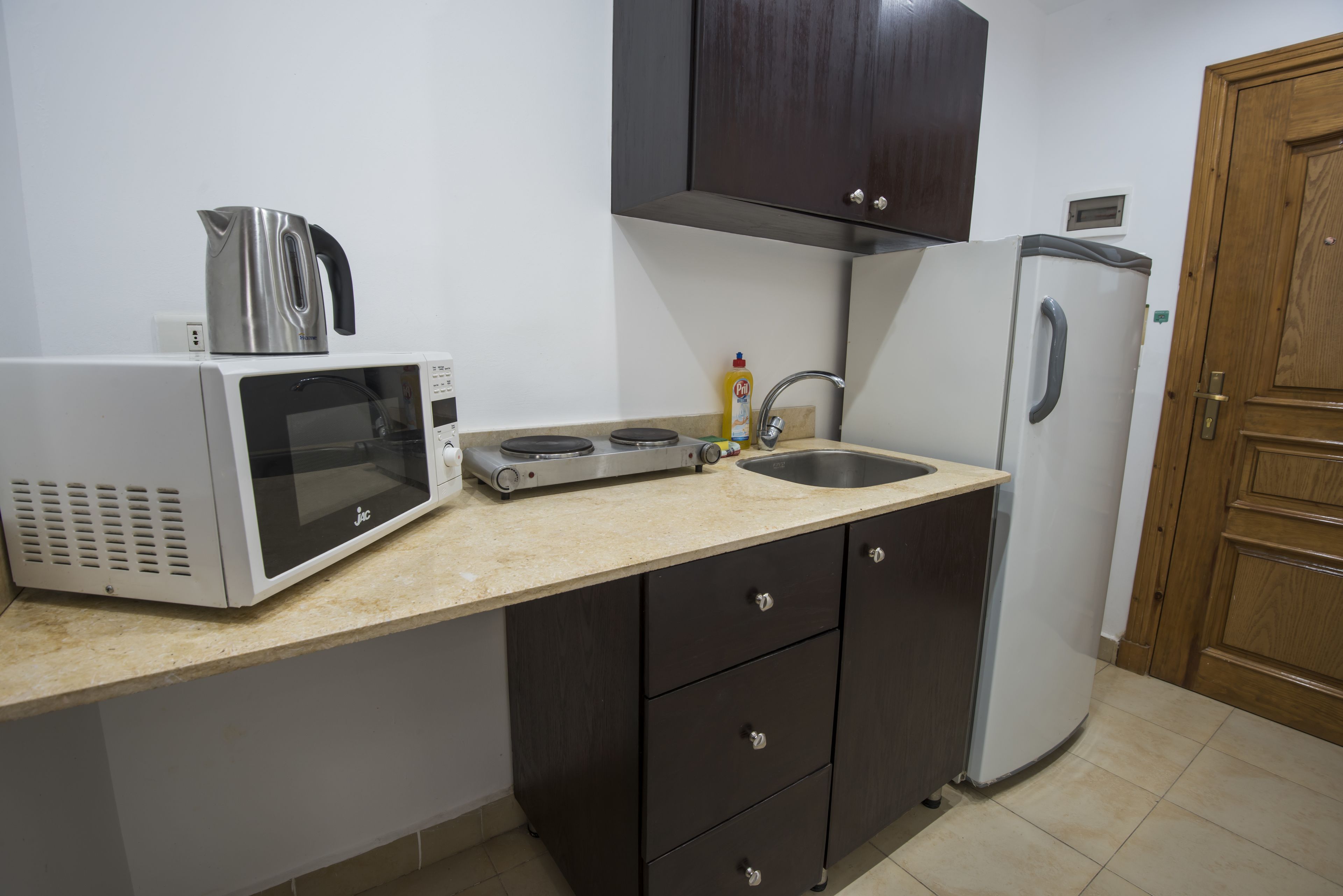 A compact kitchen with a microwave, toaster, sink, and a refrigerator.