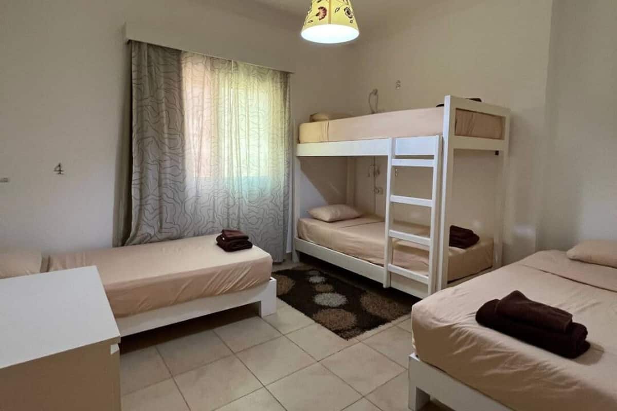 A room with bunk beds, a desk, and a window with curtains.