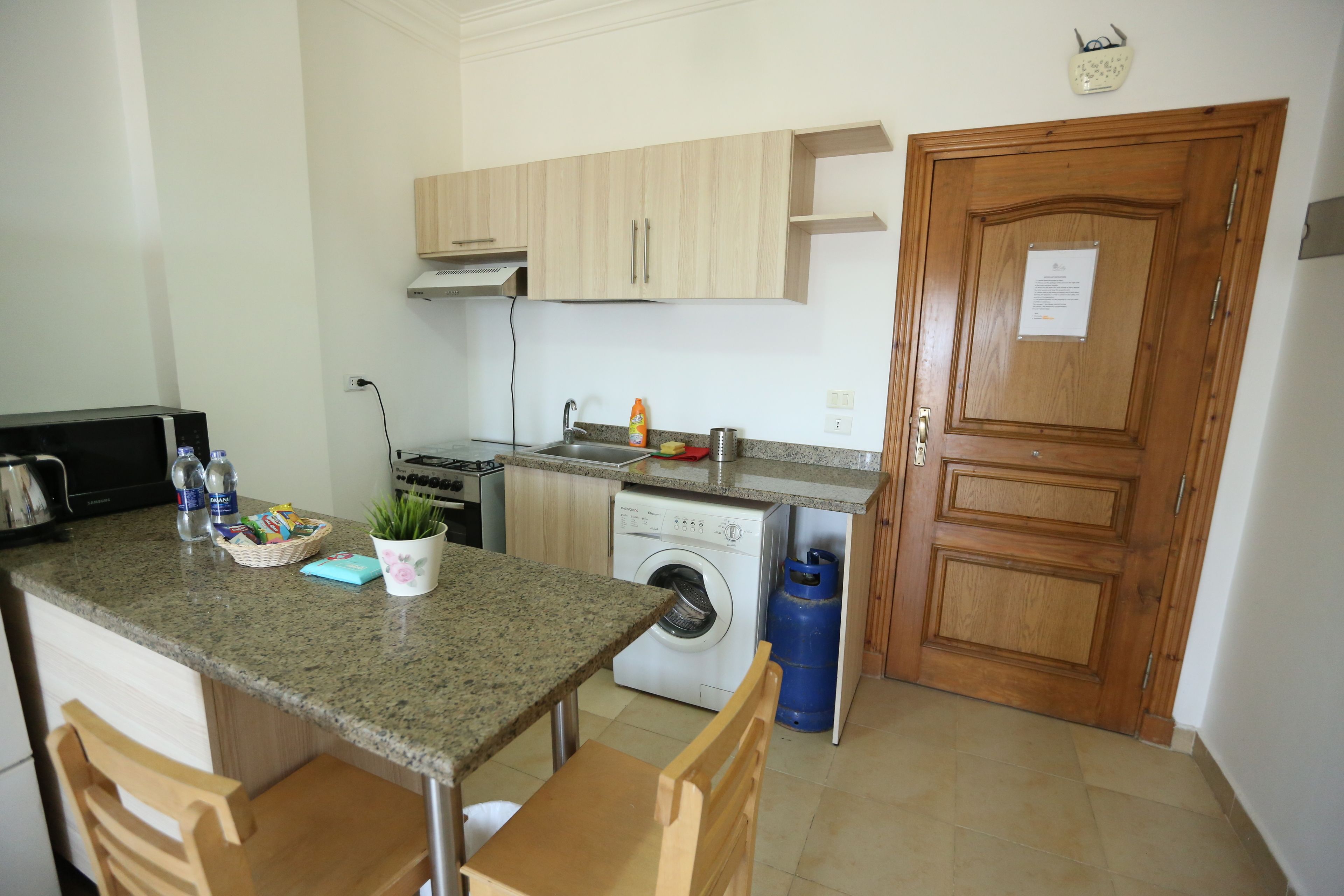 A compact kitchen with a washing machine, a sink, and wooden cabinets.