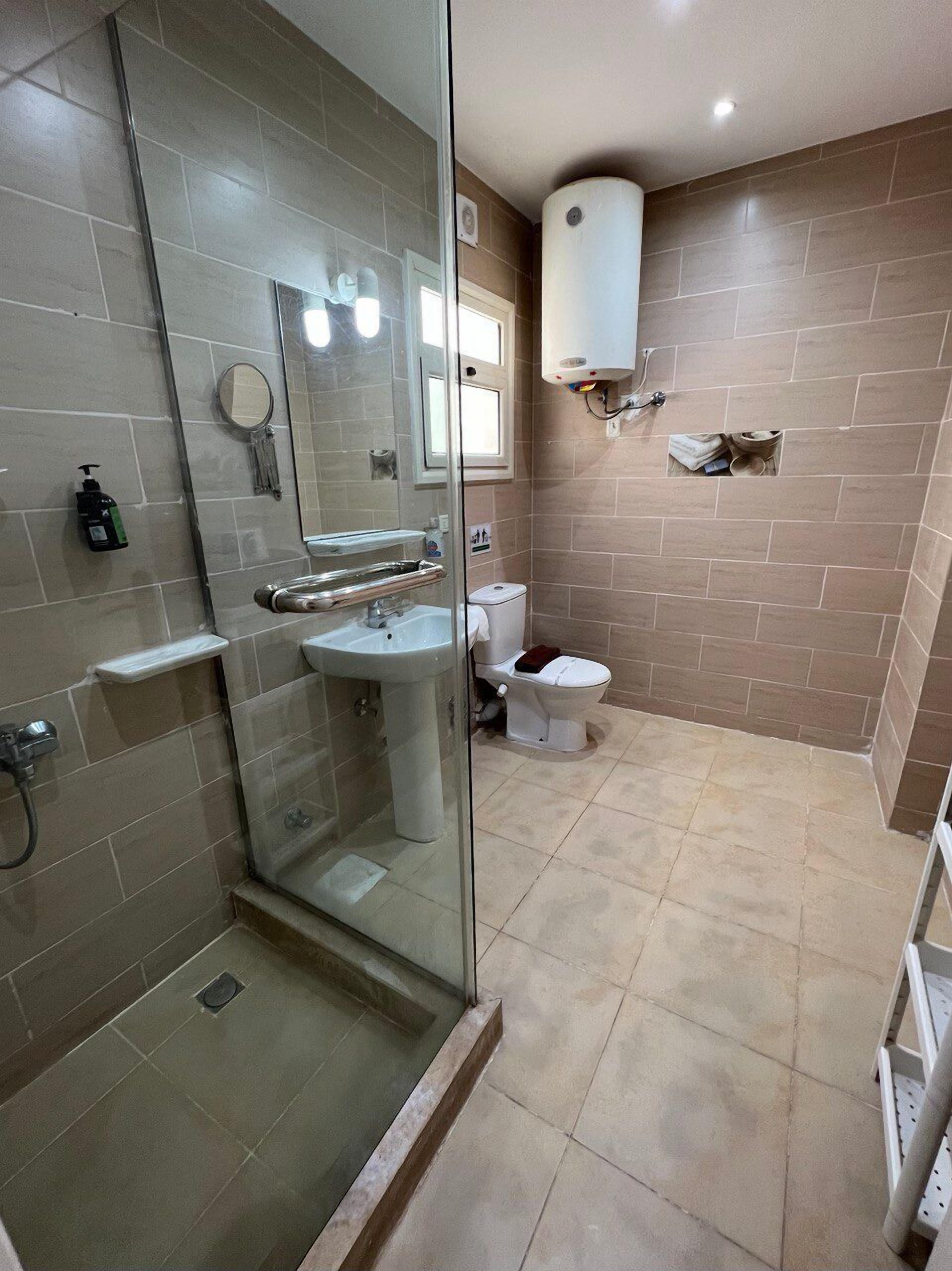 A bathroom with a glass-enclosed shower, a sink, a toilet, and a mirror.