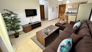 A modern living room with a brown sofa, a coffee table, a TV, and a potted plant.