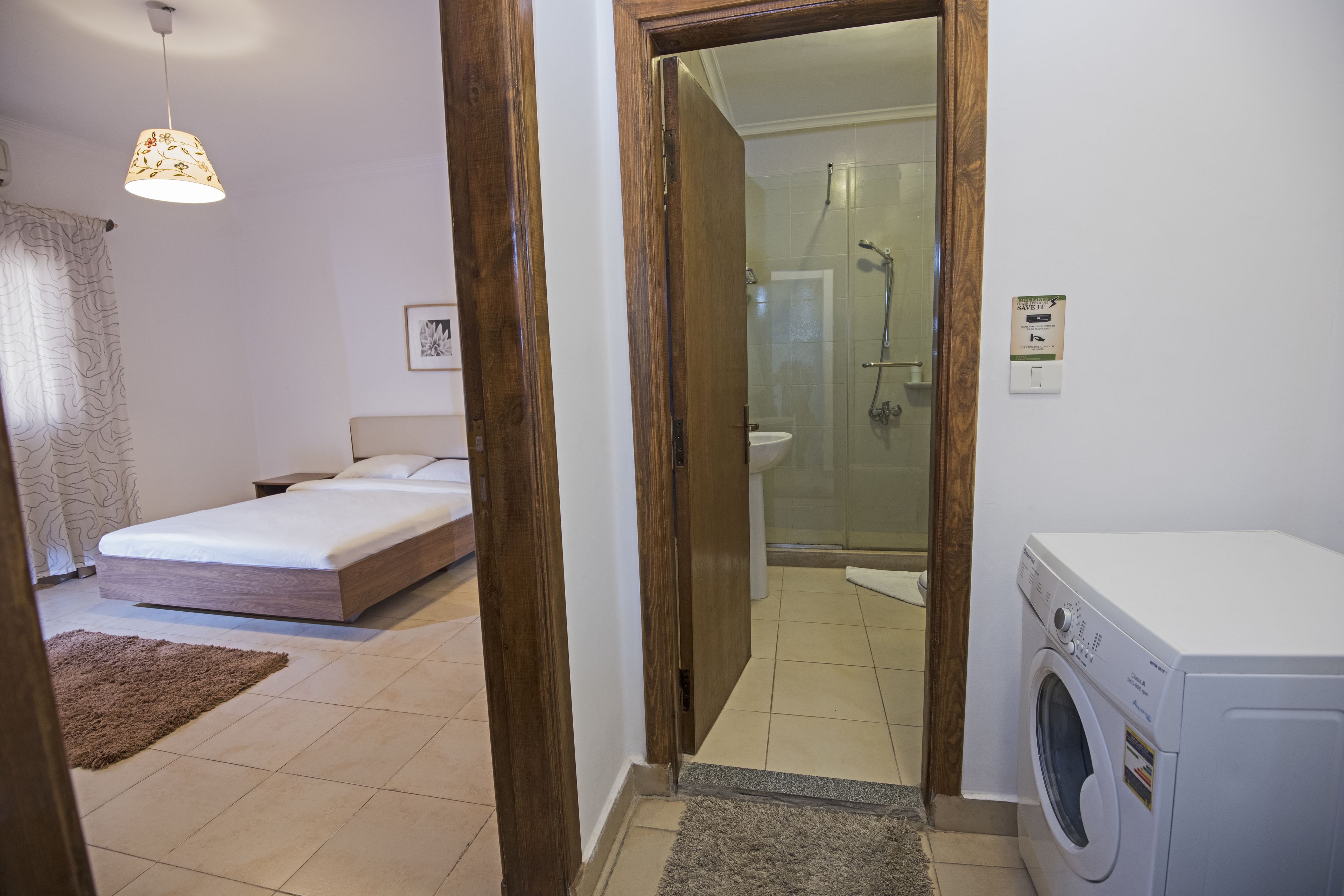 A hotel room with a bed, a washing machine, and a shower area.