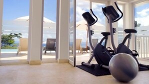 A room with a large window, an exercise bike, a stationary bike, and a yoga mat. - Vista Mare Samana Ocean View Top Floor 1 Bed (Samaná)