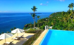 A poolside area with lounge chairs and umbrellas, overlooking a beach and ocean. - Vista Mare Samana Ocean View Top Floor 1 Bed (Samaná)