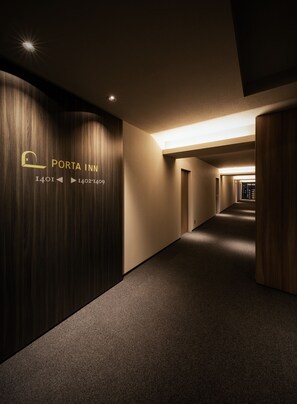 A hallway with a wooden wall on the left, a sign reading "PORTA INN I401 I402-1409", and a carpeted floor. - PORTA INN bentencho (Osaka)
