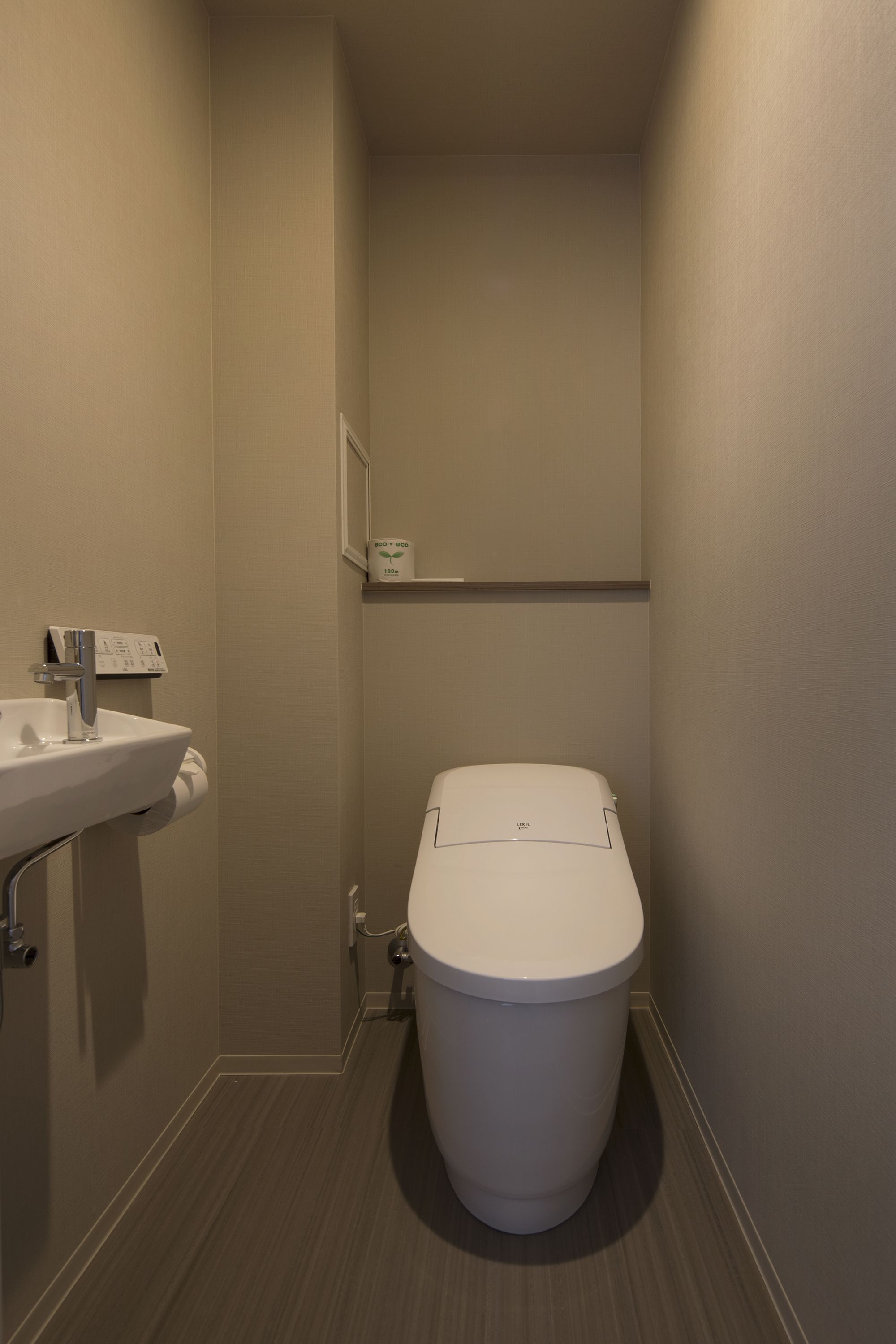 A small, modern bathroom with a white toilet, a sink, and a wall-mounted mirror.