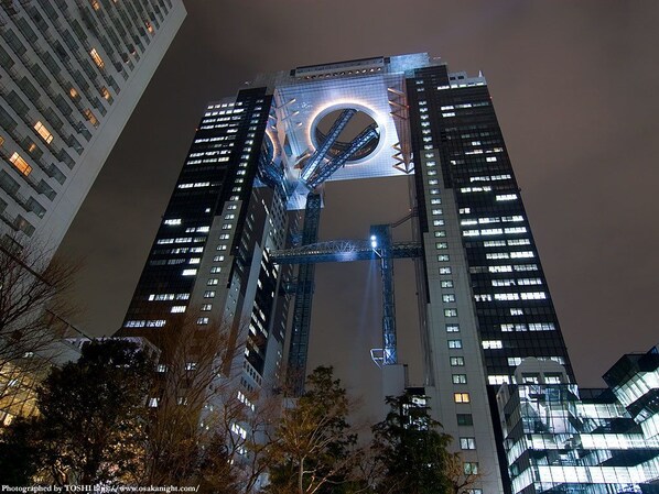 Un edificio de gran altura con un elemento arquitectónico circular en la parte superior, rodeado de otros edificios altos.