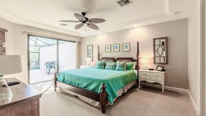 A bedroom with a large bed, a ceiling fan, a nightstand, and a window with blinds. - 3/2.5 home, custom designed with vacation in mind. (Marco Island)