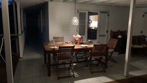 A dining area with a wooden table set for four, surrounded by chairs.
