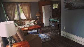 Ein gemütlicher Wohnbereich mit Sofa, Esstisch, Lampe und Kühlschrank.