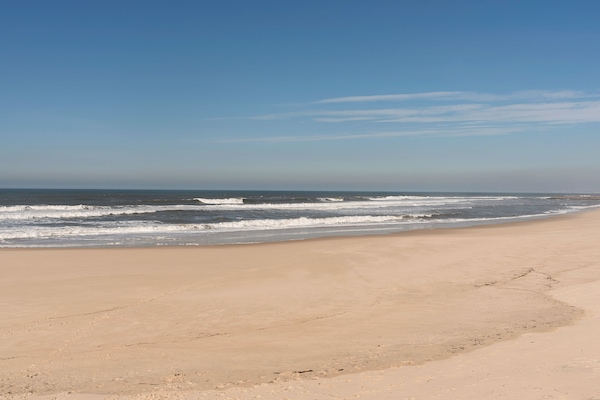 Una playa cerca, arena blanca, sombrillas, 2 bares en la playa