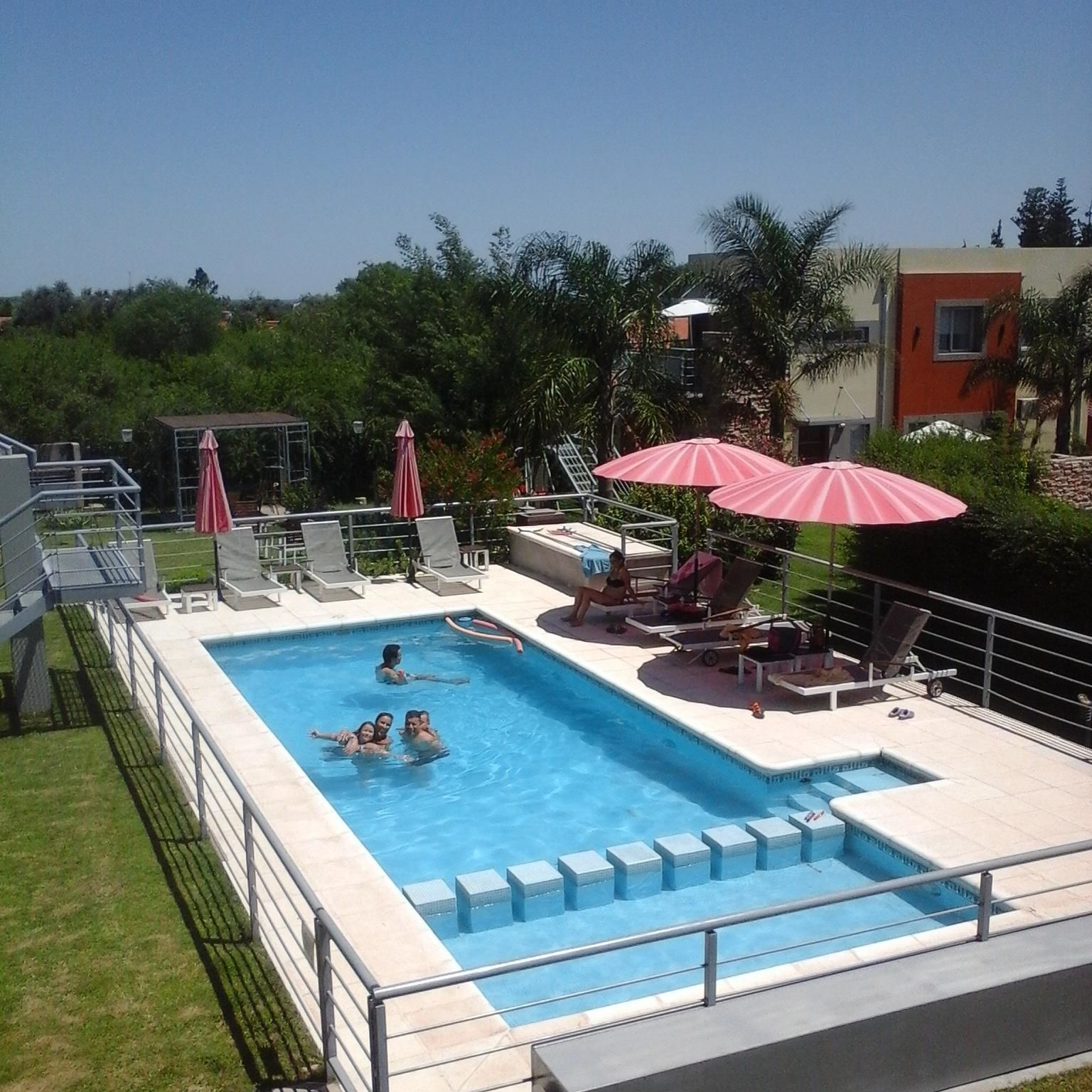Una piscina rettangolare con un trampolino e sedie a sdraio.