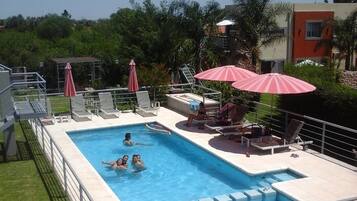 Una piscina rettangolare con un trampolino e sedie a sdraio.