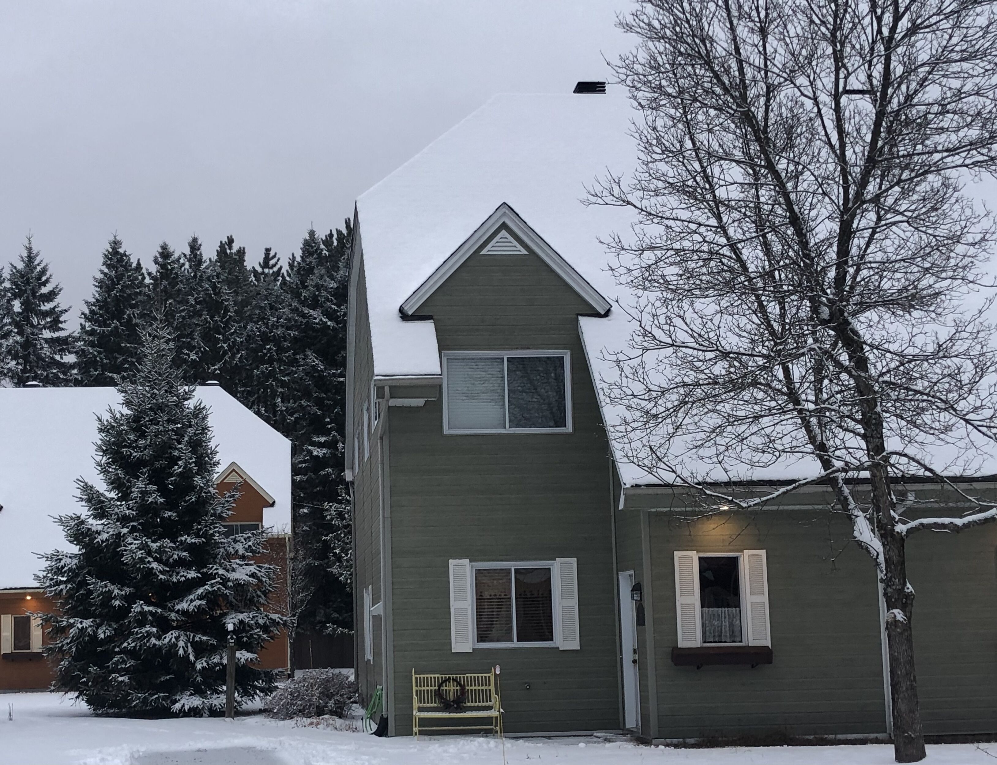 A two-story house with a snow-covered roof and a small porch.