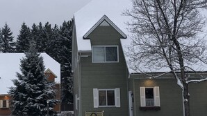 Una casa de dos pisos con techo nevado y un porche pequeño.