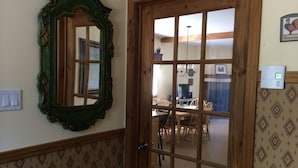 Una habitación con puerta de madera, un espejo y papel tapiz estampado.