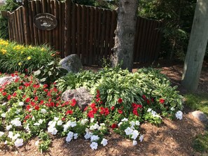 A garden with red and white flowers, a wooden fence, and a sign that reads "Domaine du Lac".