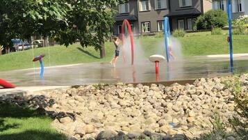Un espace de jeux aquatiques doté de plusieurs jets d’eau et bordé de rochers.
