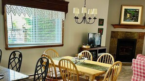 Un comedor con una mesa y sillas de madera, un tapete estampado y una chimenea.