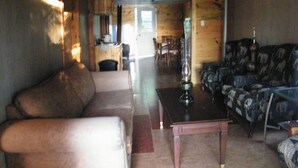 A log cabin interior with a living room, a dining area, and a kitchen.
