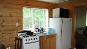 A compact kitchen with a stove, refrigerator, and window.
