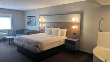 A modern hotel room with a large bed, bedside tables, a desk, and a bathroom with a bathtub.