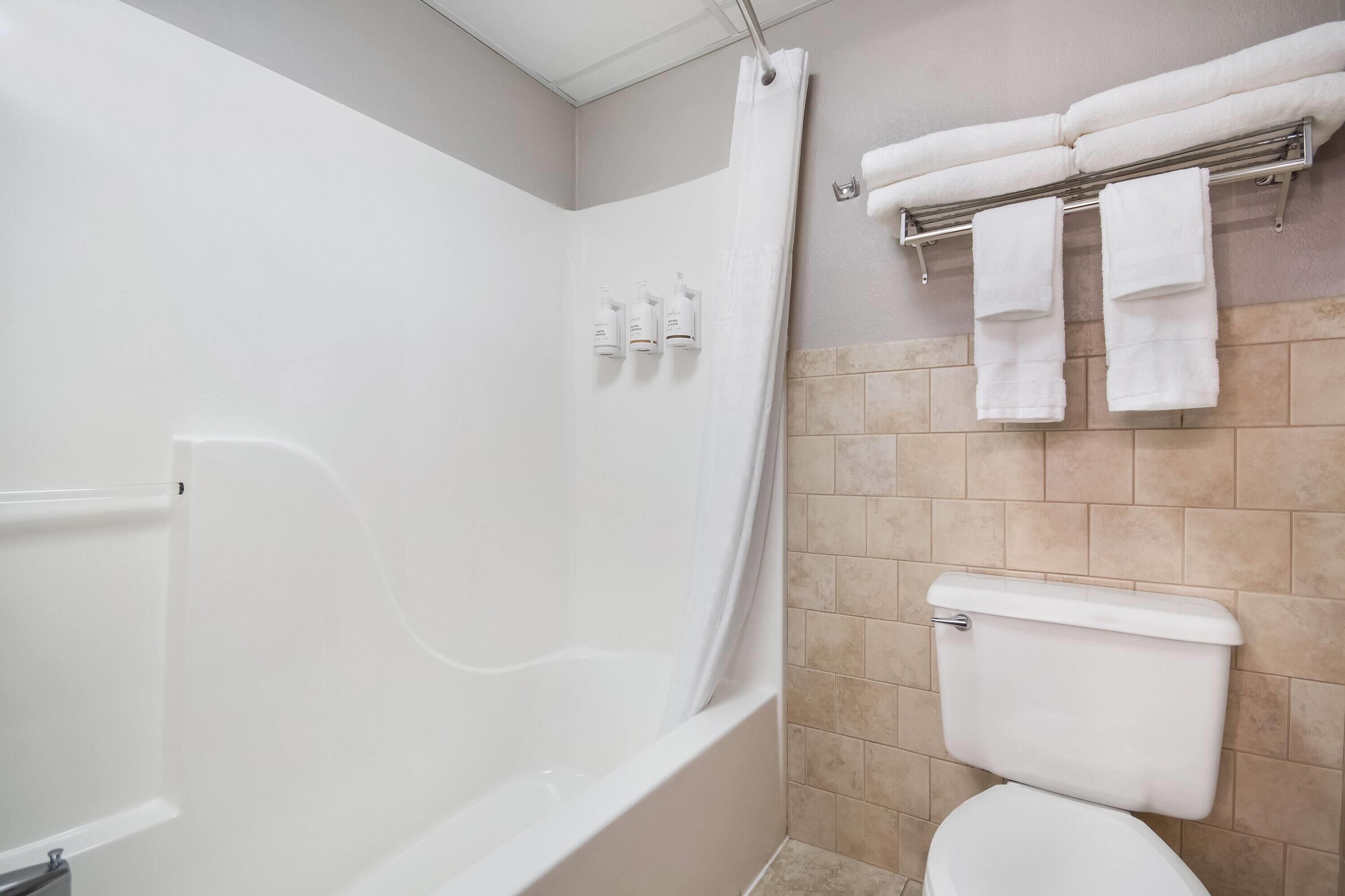 A bathroom with a bathtub, toilet, and towel rack.