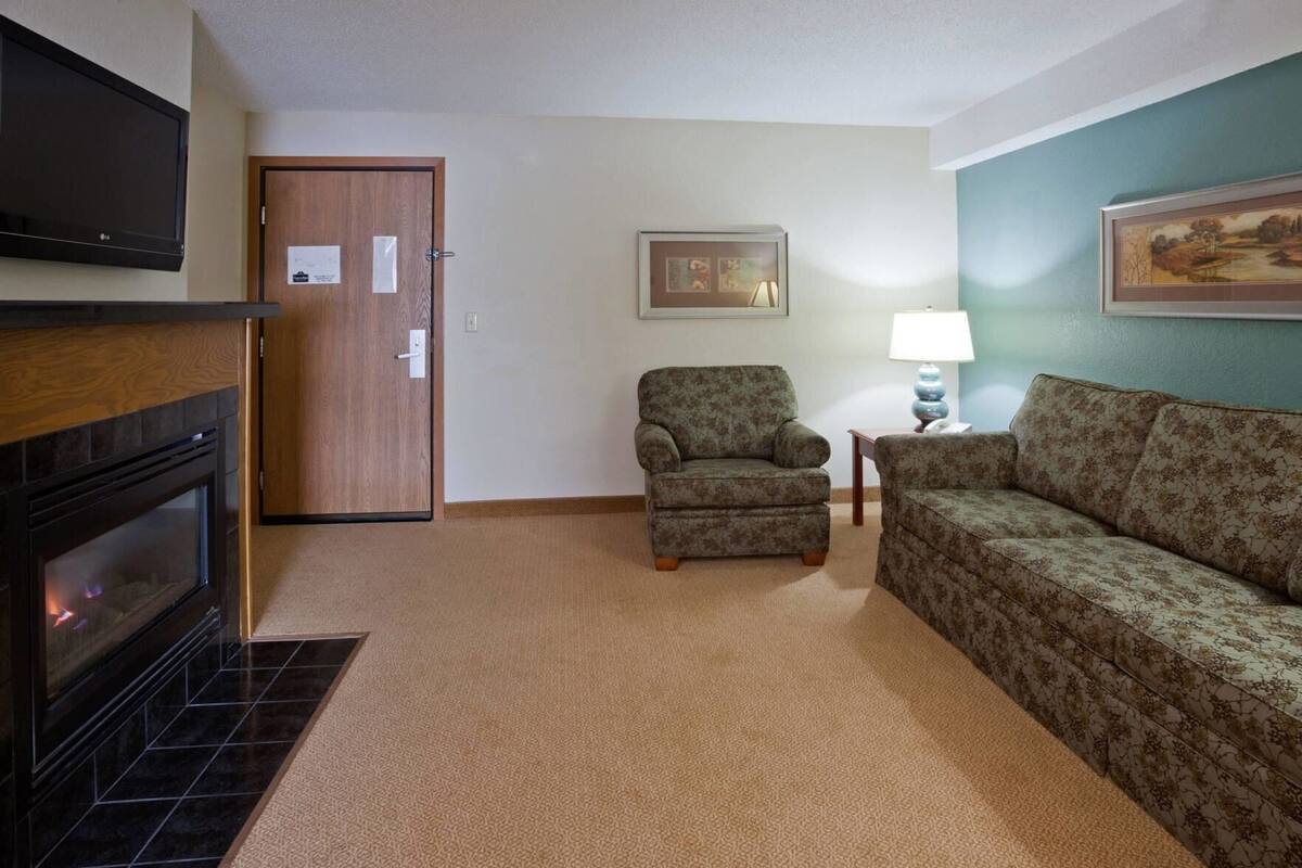 A living room with a fireplace, a sofa, a chair, a lamp, and a painting on the wall.