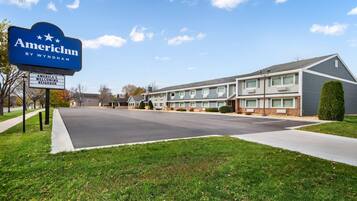 A two-story motel with a sign reading "AmericInn by Wyndham" and a welcoming neighbor sign.