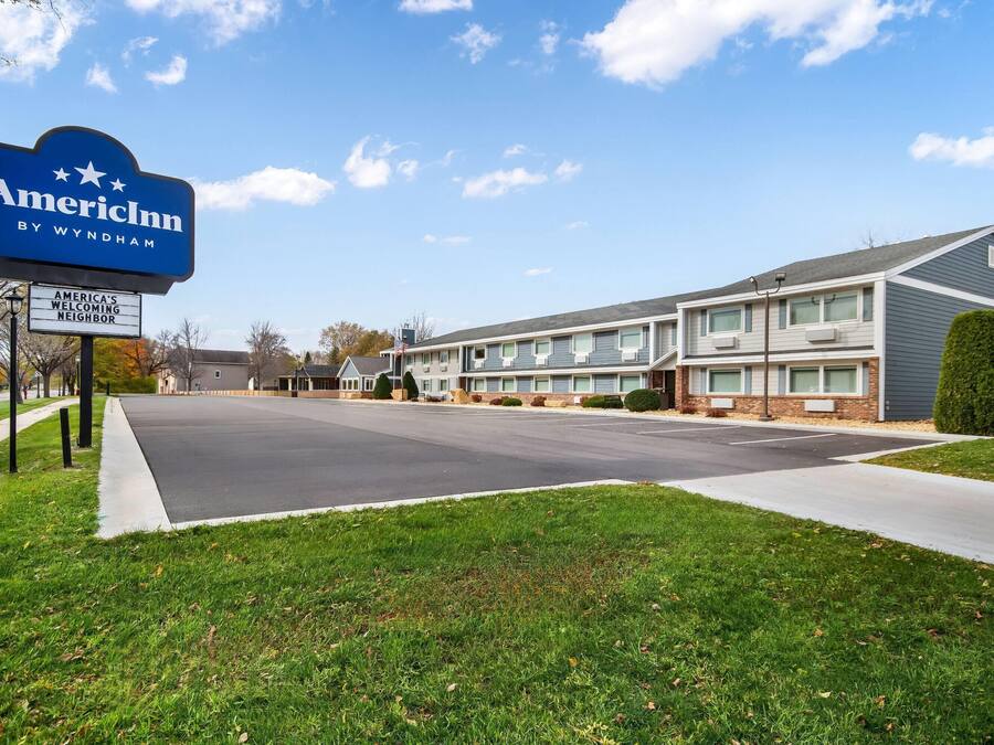 A two-story motel with a sign reading "AmericInn by Wyndham" and a welcoming neighbor sign.