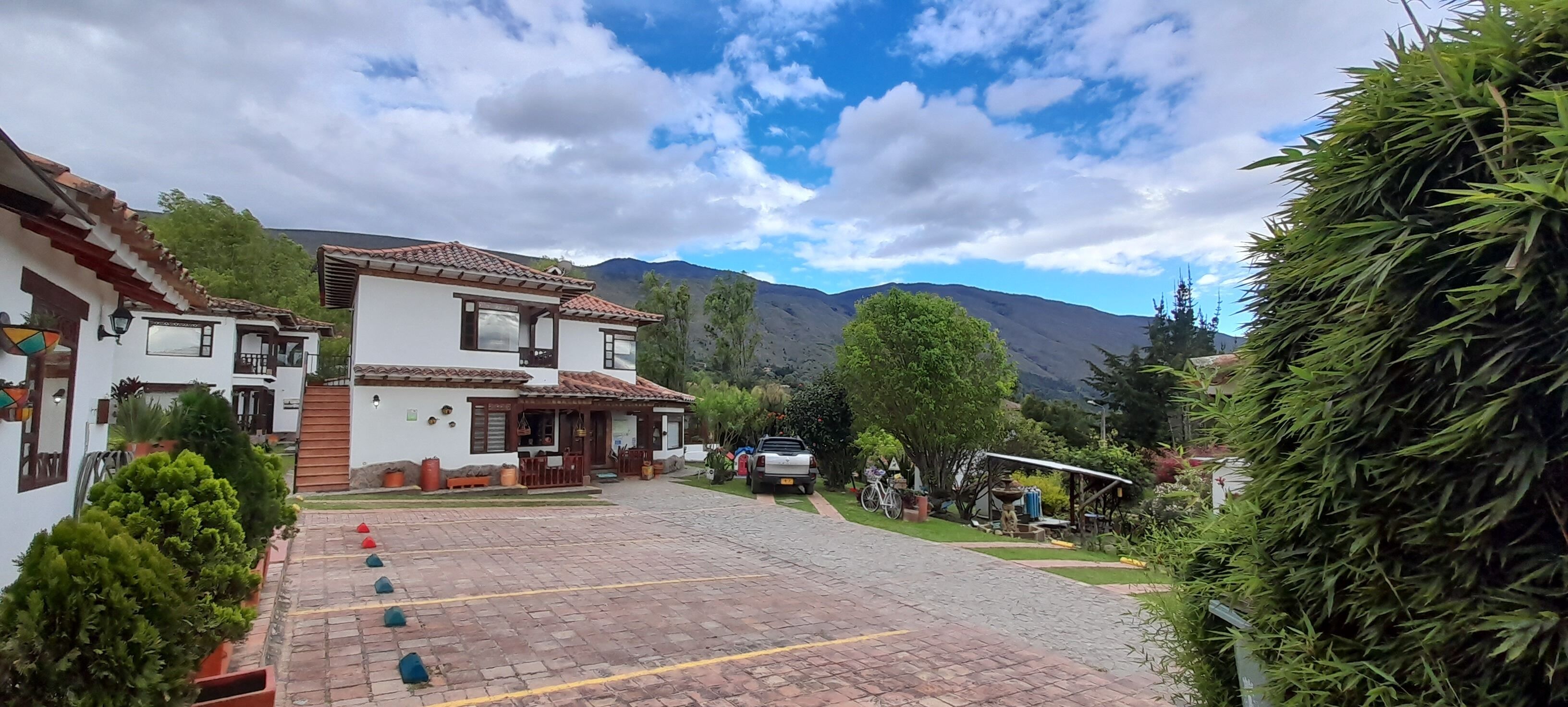 Un patio empedrado con edificios, una montaña al fondo y un cielo despejado.