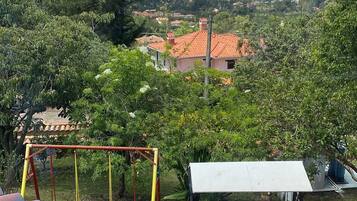 Un patio con una mesa y un columpio, con vista a una zona residencial con casas y montañas al fondo.
