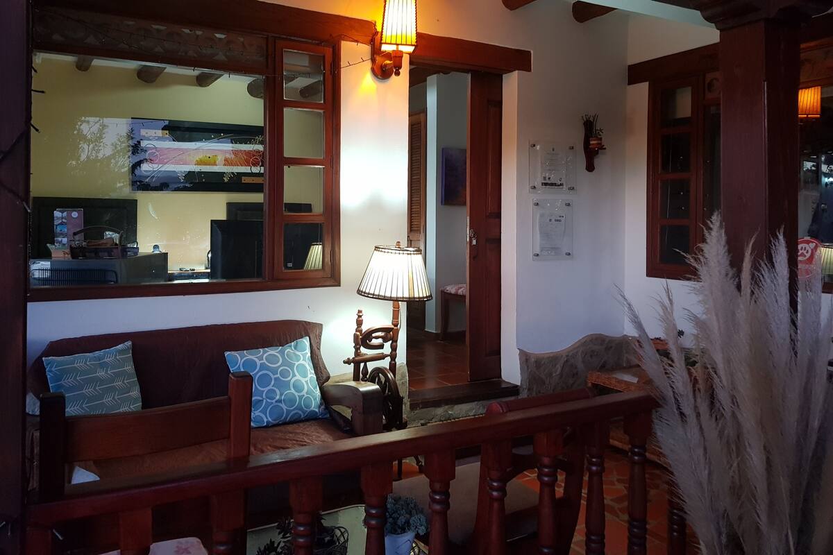 Una sala de estar acogedora con un sofá de madera, una lámpara y un espejo decorativo.