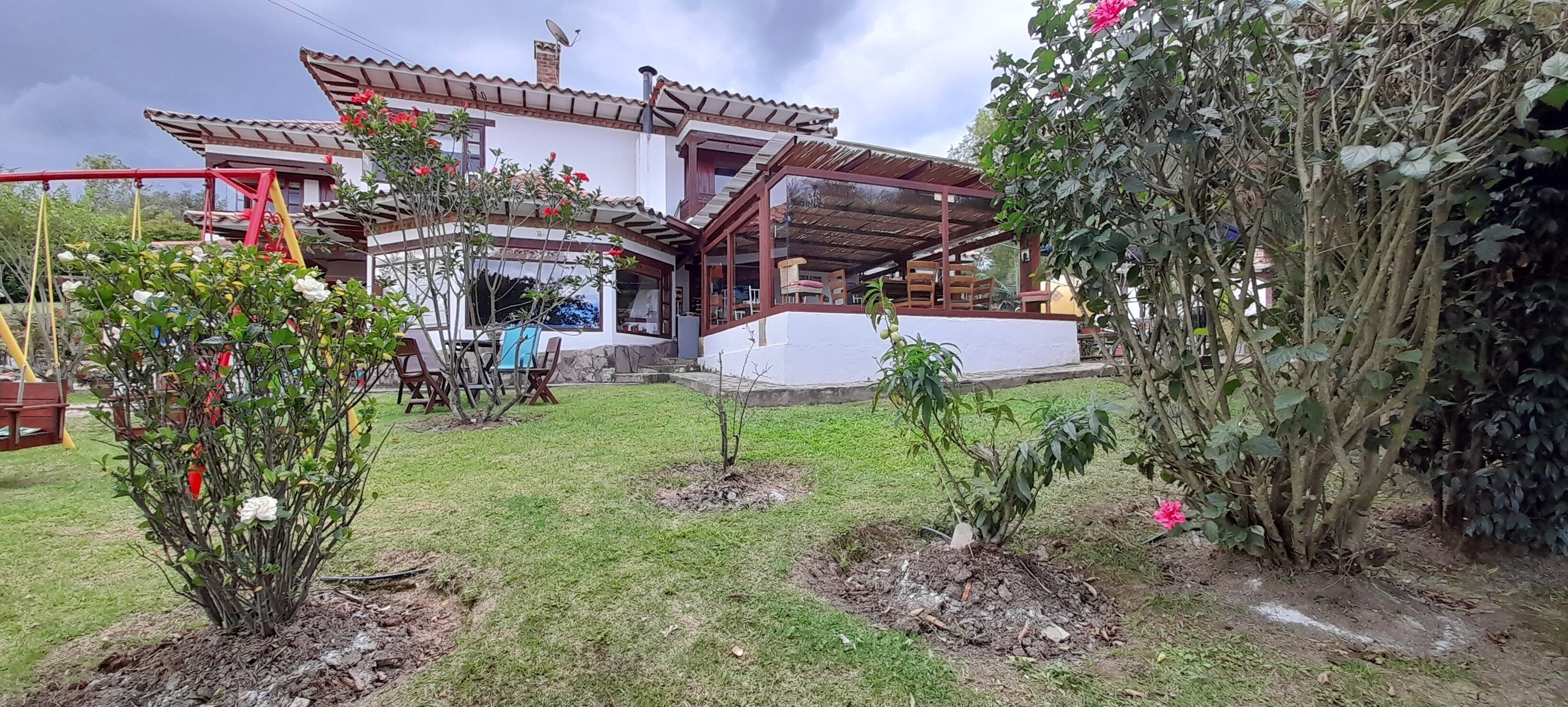 A house with a patio, a covered outdoor seating area, and a garden with various plants.