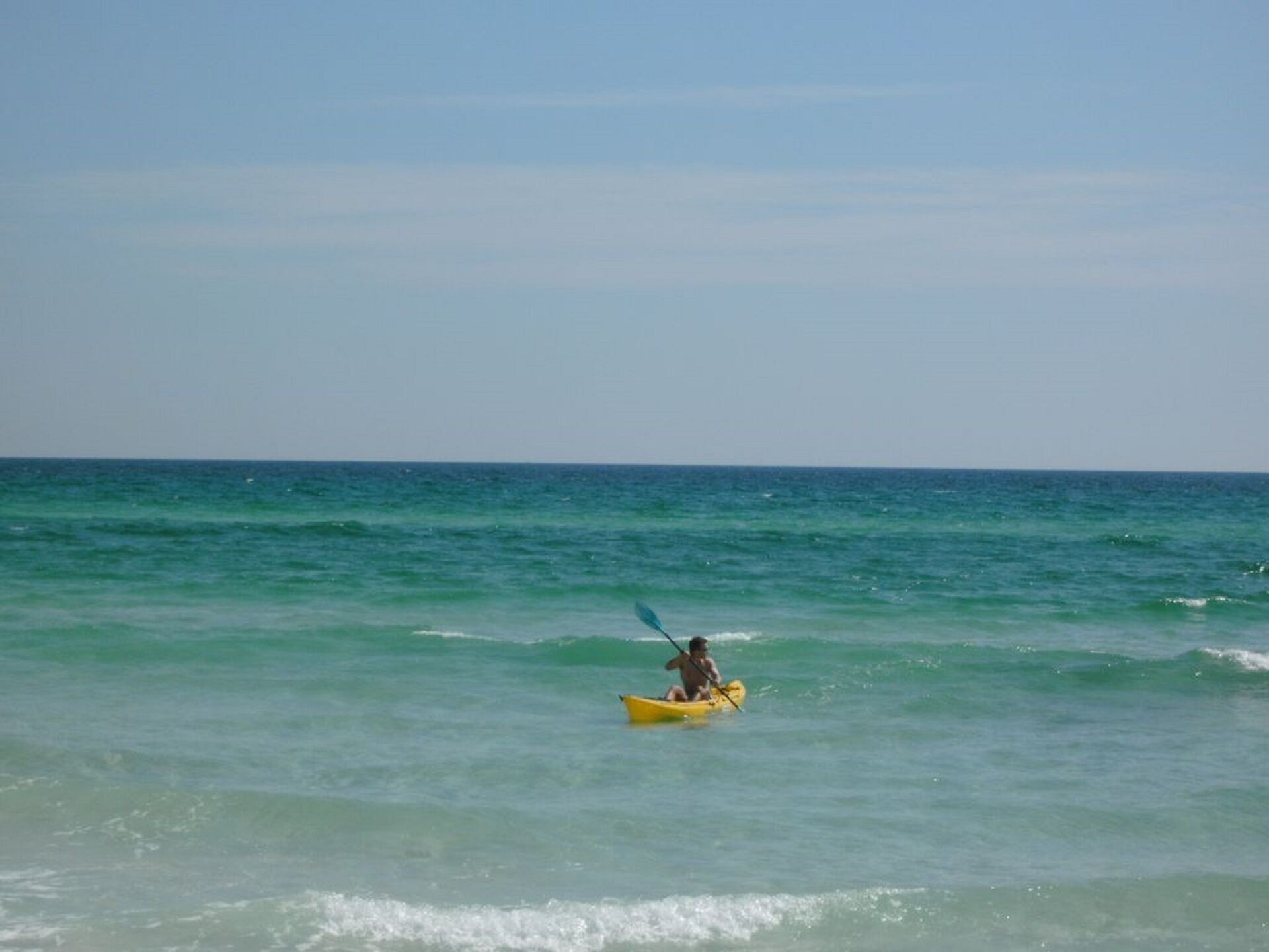 Une personne pratiquant le kayak sur une mer calme.