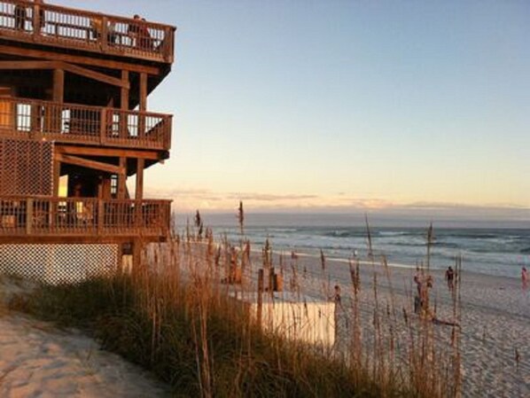 A wooden beach house with multiple balconies overlooking the ocean.