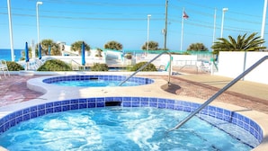 A swimming pool with a curved design, surrounded by a tiled deck and a sandy area. -  So Cozy & Serene Perfect Getaway Gulf Front Studio  
Private  Balcony Bch Srv  (Miramar Beach)