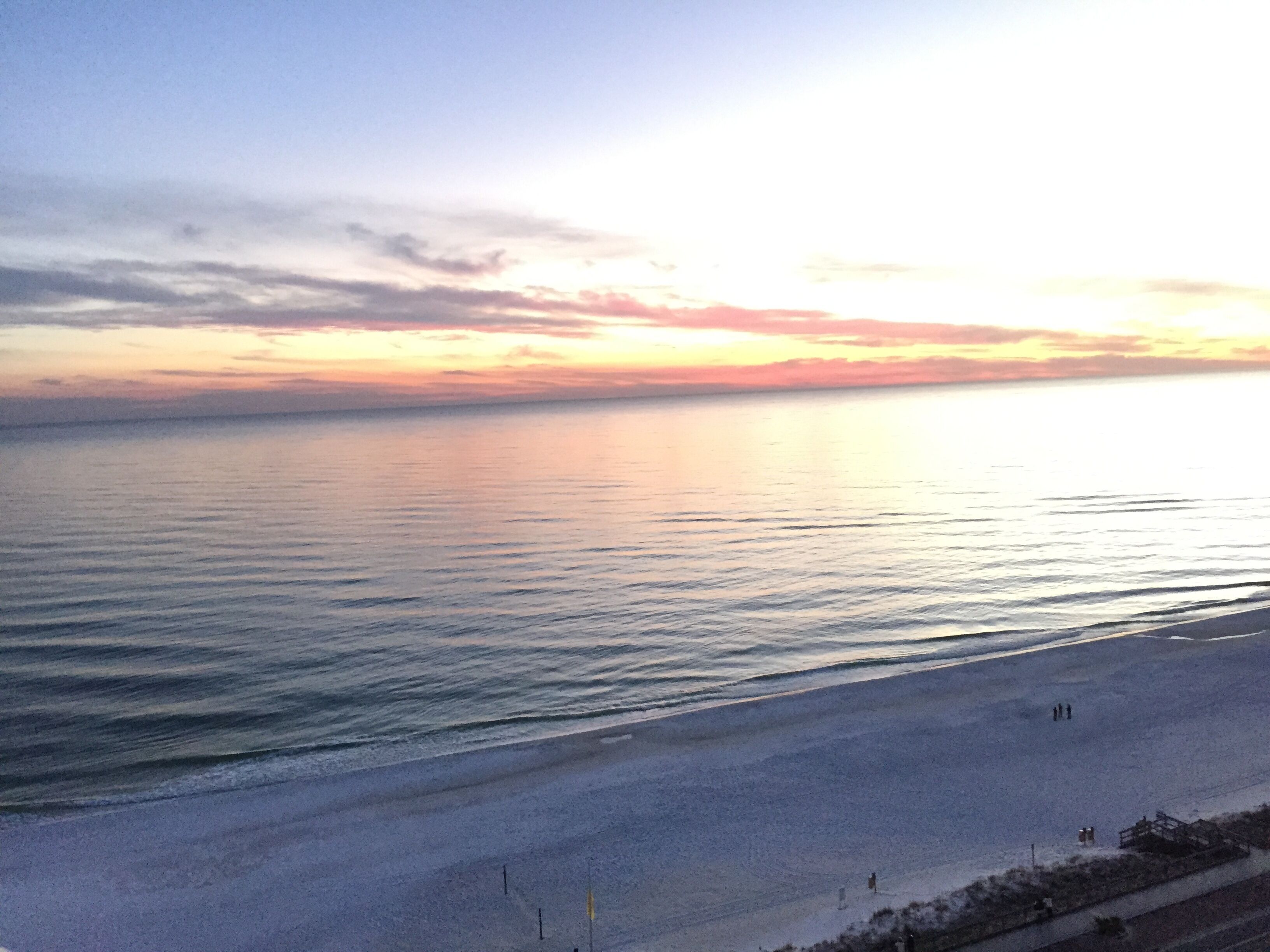 Ein Strand mit ruhiger See und Sonnenuntergang.