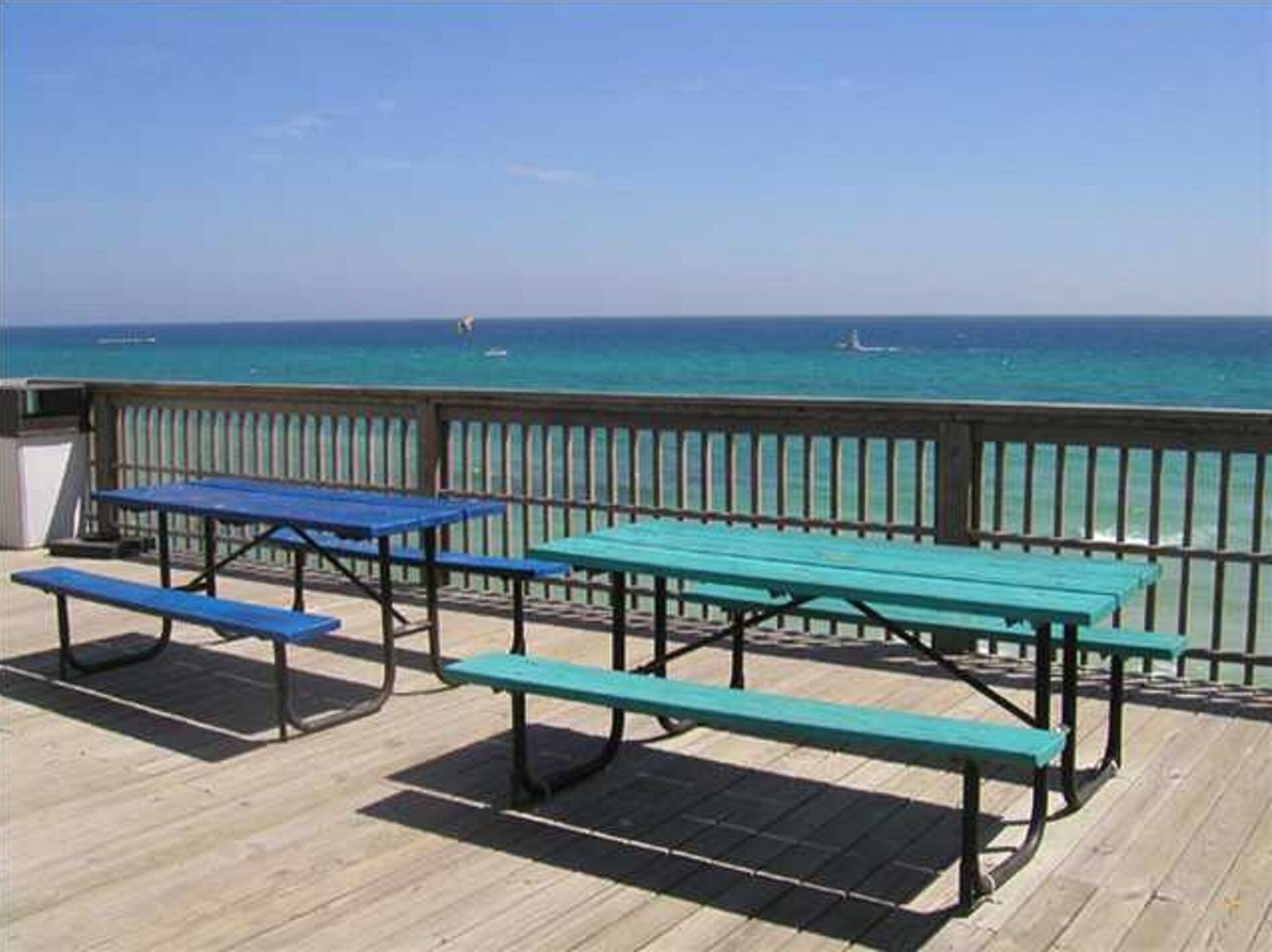 Een houten terras met picknicktafels met uitzicht op de oceaan.