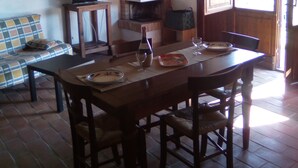 Un coin repas avec une table et des chaises en bois, un téléviseur posé sur une petite table et une cheminée.