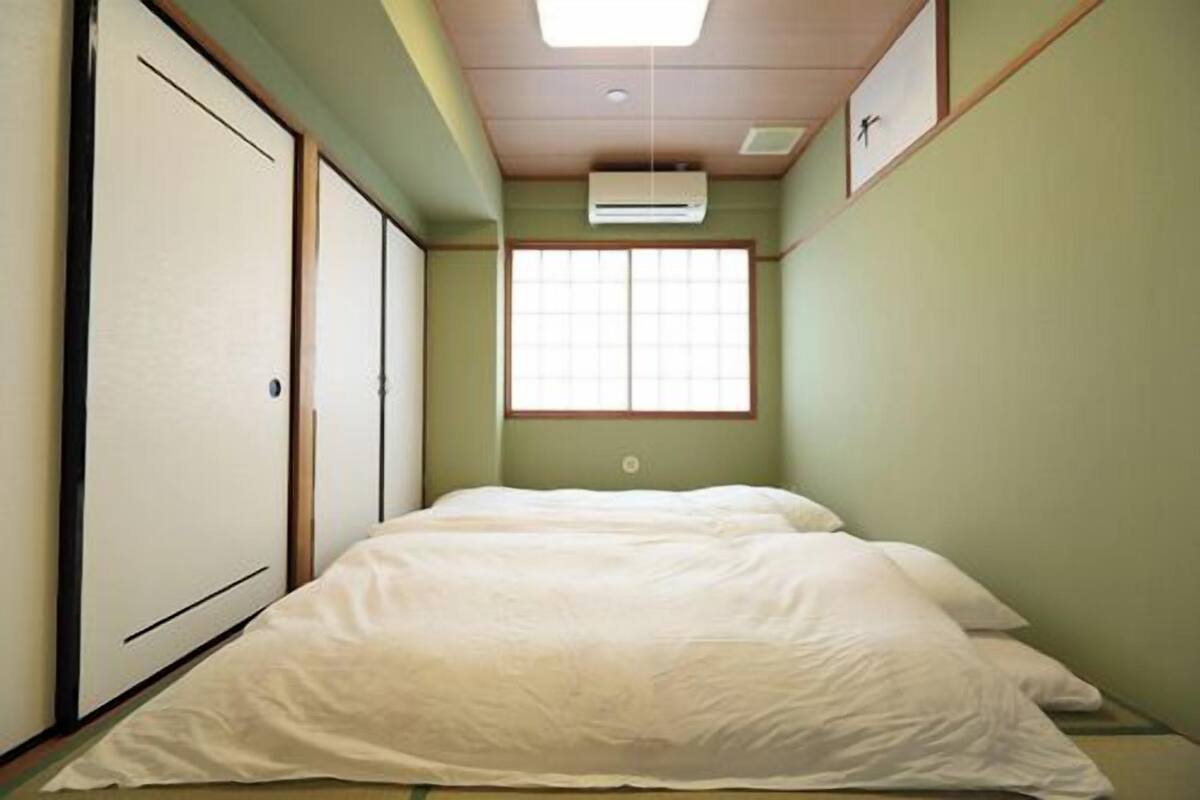 A narrow room with a bed, a window, and an air conditioner.