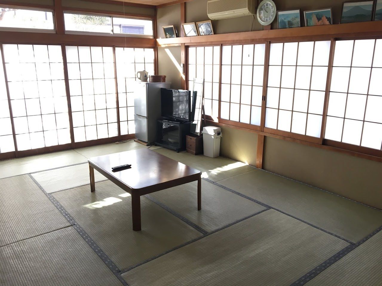 A traditional Japanese room with tatami flooring, a low table, a television, and a heater.