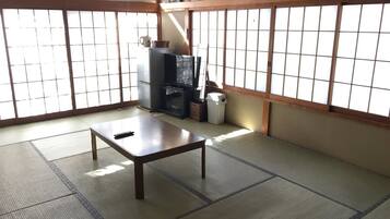 A traditional Japanese room with tatami flooring, a low table, a television, and a heater.