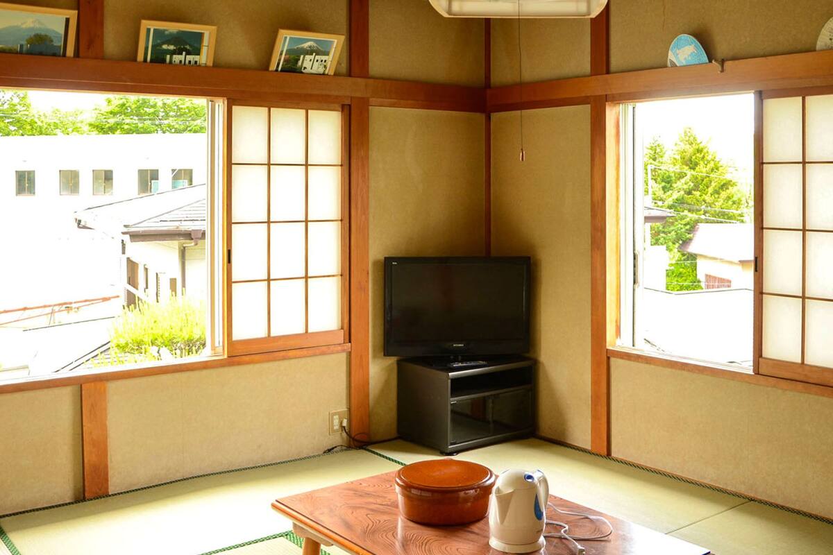 A traditional Japanese room with tatami flooring, a television, and a futon bed.