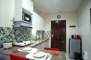 A kitchen with a microwave, stove, sink, and a refrigerator.