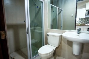 A bathroom with a toilet, a sink, and a glass shower enclosure. - SR Vacation Rental - Spianada Residential Condominium (Cebu City)