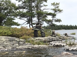 A traditional totem pole and a stone cairn by a lake surrounded by trees. - Georgian Bay Cottage Rentals - Mactier, Ontario (Mactier)