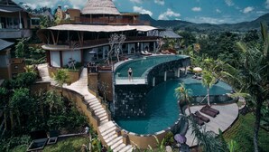 Un resort con una piscina grande, una cascada y vistas a la montaña.