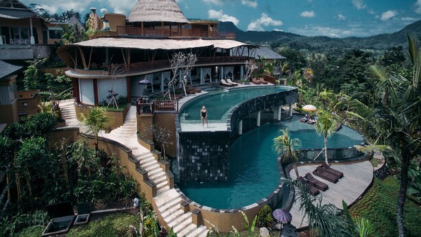 Een resort met een groot zwembad, een waterval en uitzicht op een berg.